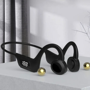 Black wireless earbuds with a digital display on a light surface.