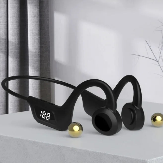 Black wireless earbuds with a digital display on a light surface.