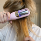 Person using a pink hair straightening device on their hair